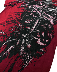 A close-up of a red graphic t-shirt featuring a large black and white print of a skull holding a sword, with a pumpkin and gothic details.
